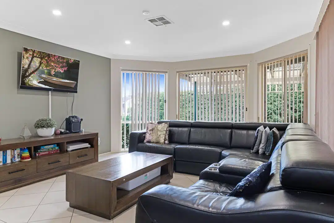 Living room with black leather sofa, wooden coffee table and a television.