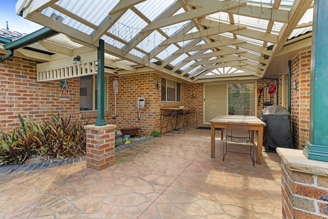 Undercover outdoor entertainment area with wooden table and seating.