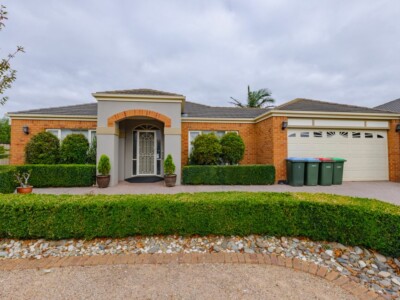 Large red brick SIL house with hedges in the front garden.