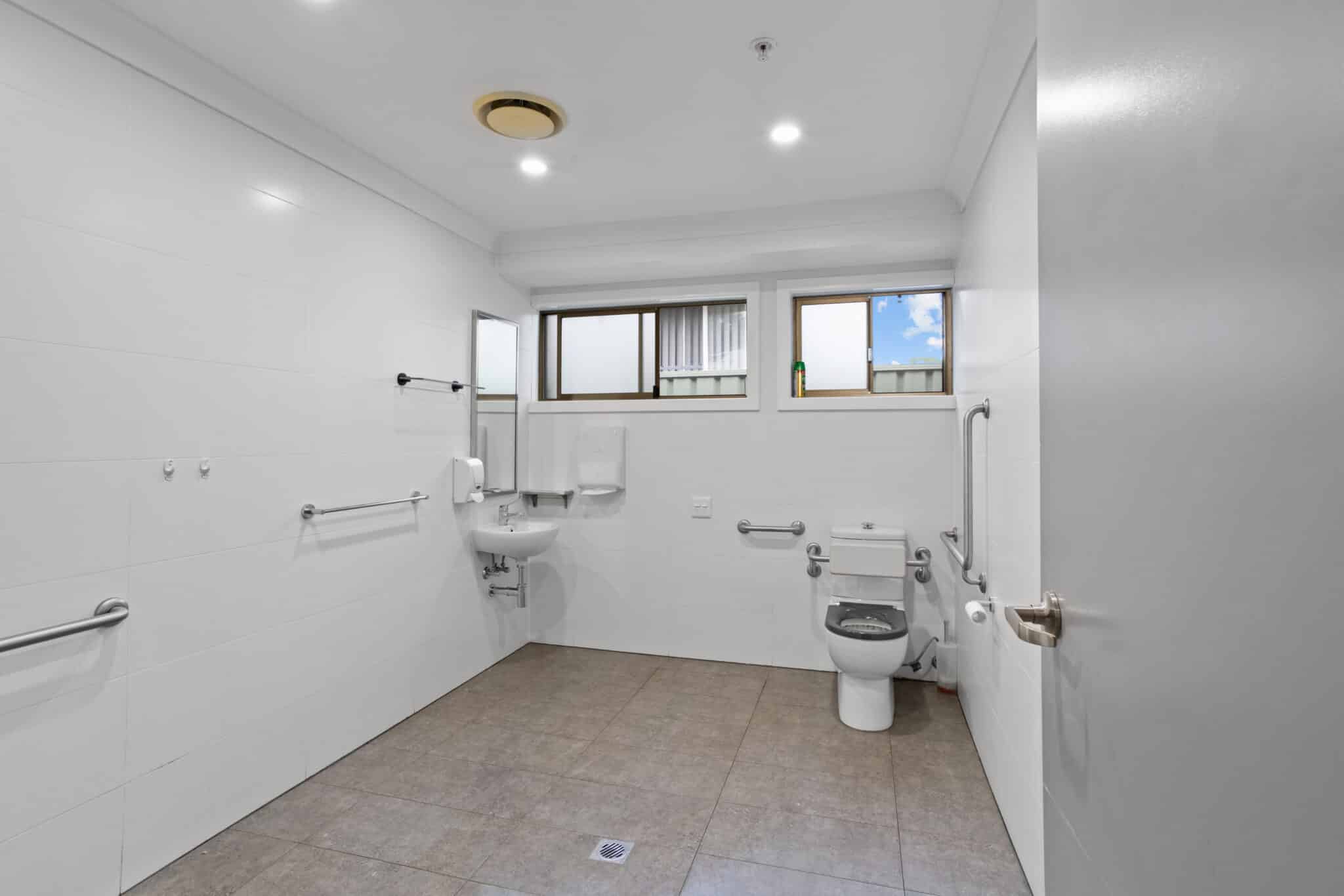 Large accessible bathroom with a shower and grab rails.