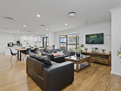 Living room with a television, wooden coffee table and two black leather sofas.
