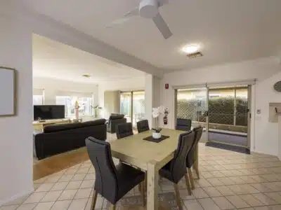 Open plan dining area featuring a large table with leather chairs. Living room can be seen in the background.
