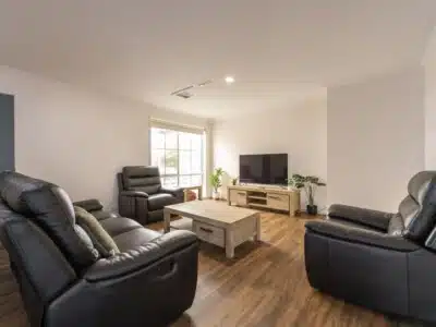 Living room with black leather sofas, wooden coffee table and television stand with a large television.