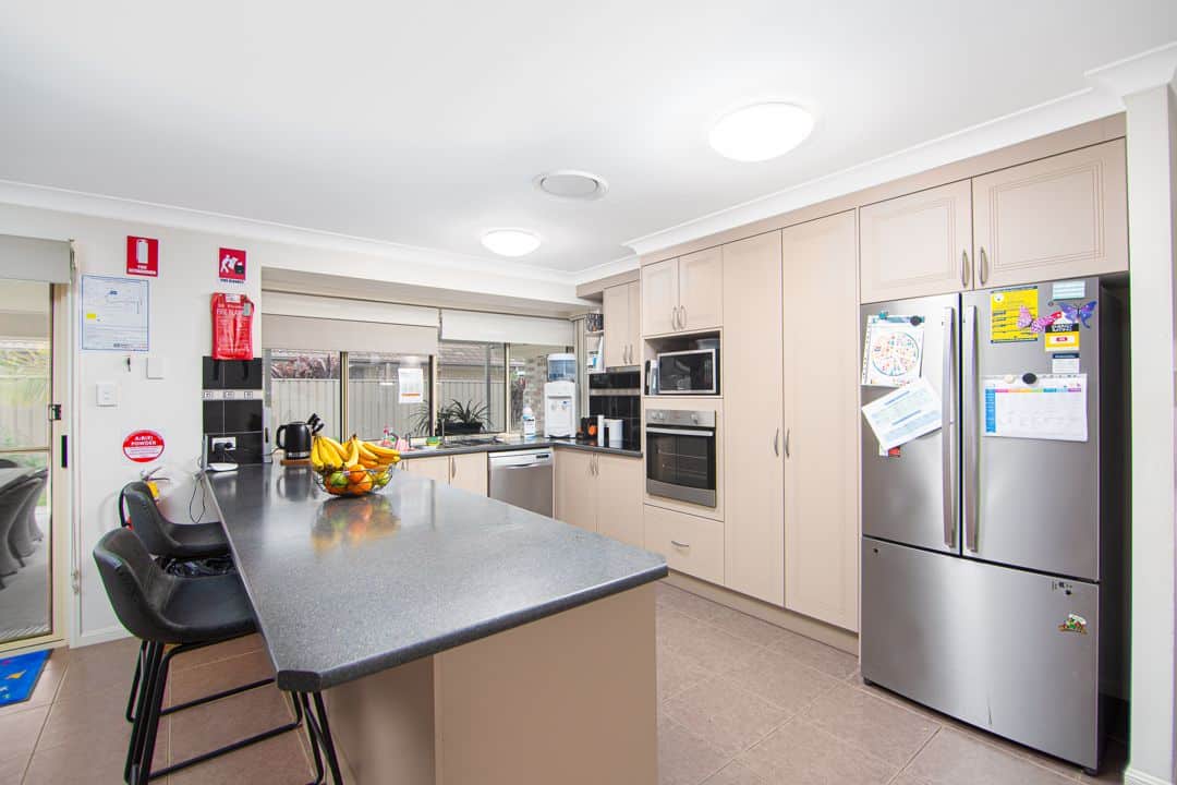 Kitchen with cream coloured cabinets and marble benchtop.