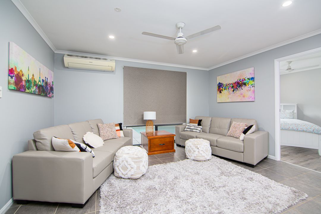 Large living room with two grey sofas, a grey rug and two small ottoman.