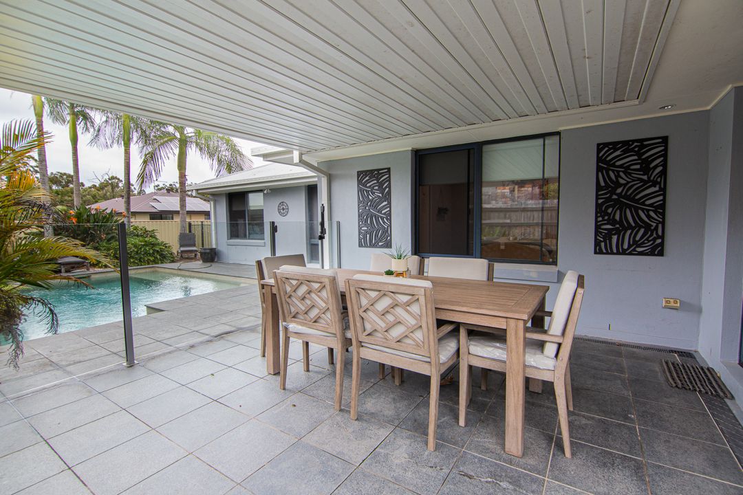 Outdoor backyard area with a dining table and chairs and a large swimming pool.