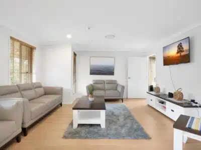 Living room featuring three large leather sofas, wooden coffee table, side table and wall mounted television.