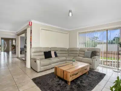 Living room with a large grey corner sofa, dark grey rug, wooden coffee table and decorative plants.