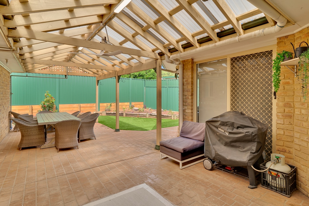 Large backayrd with outdoor entertainment area including wooden table, chairs and a barbeque.