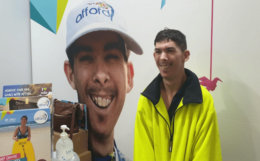 Josh at Disability expo standing with a photo of himself