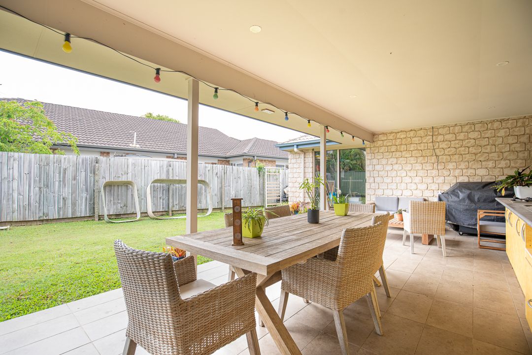 Large backyard with outdoor entertainment area including wooden table and chairs.