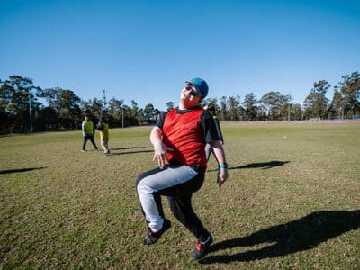 Young man in an Afford hat skipping outside in a park