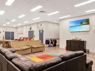 Lounge area with a large sofa and two smaller sofas. There is a television mounted on the wall.